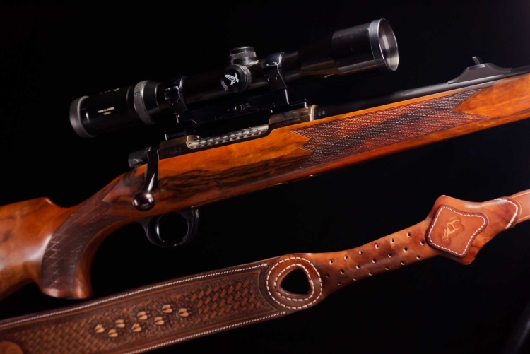 Left view of the rifle with the scope and the worked leather sling