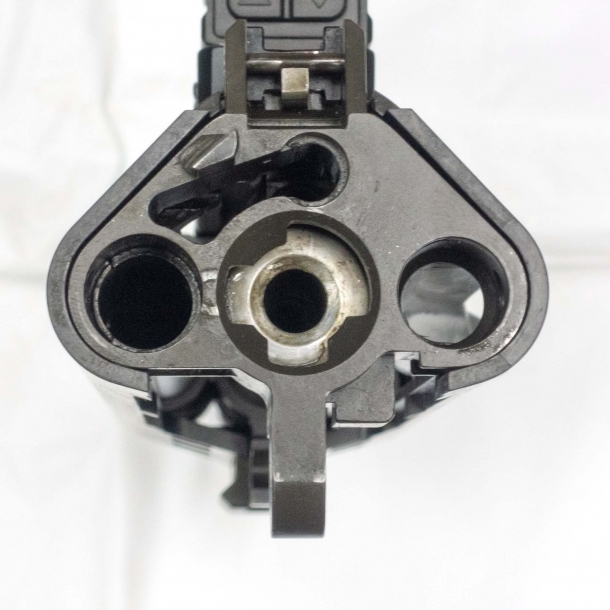 Rear view of the upper receiver. On top is the seat of the contact point between the bolt group and the ambidextrous charging handle; on the bottom, from left to right, are respectively the gas piston seat; the chamber; and the forward chute for spent cases